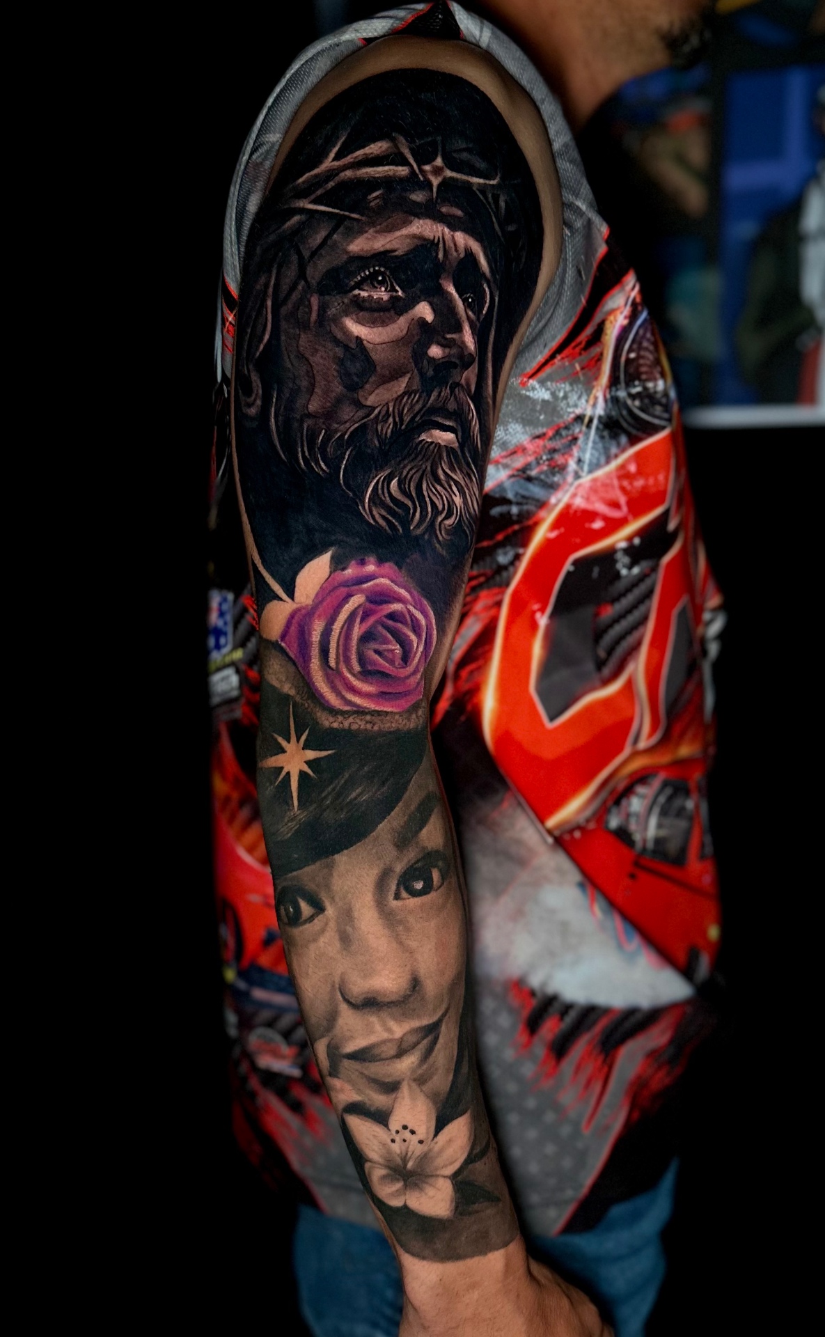Black and grey sleeve with Jesus, a color rose, a star and a portrait by Ramón Santiago at R INKS ARTS