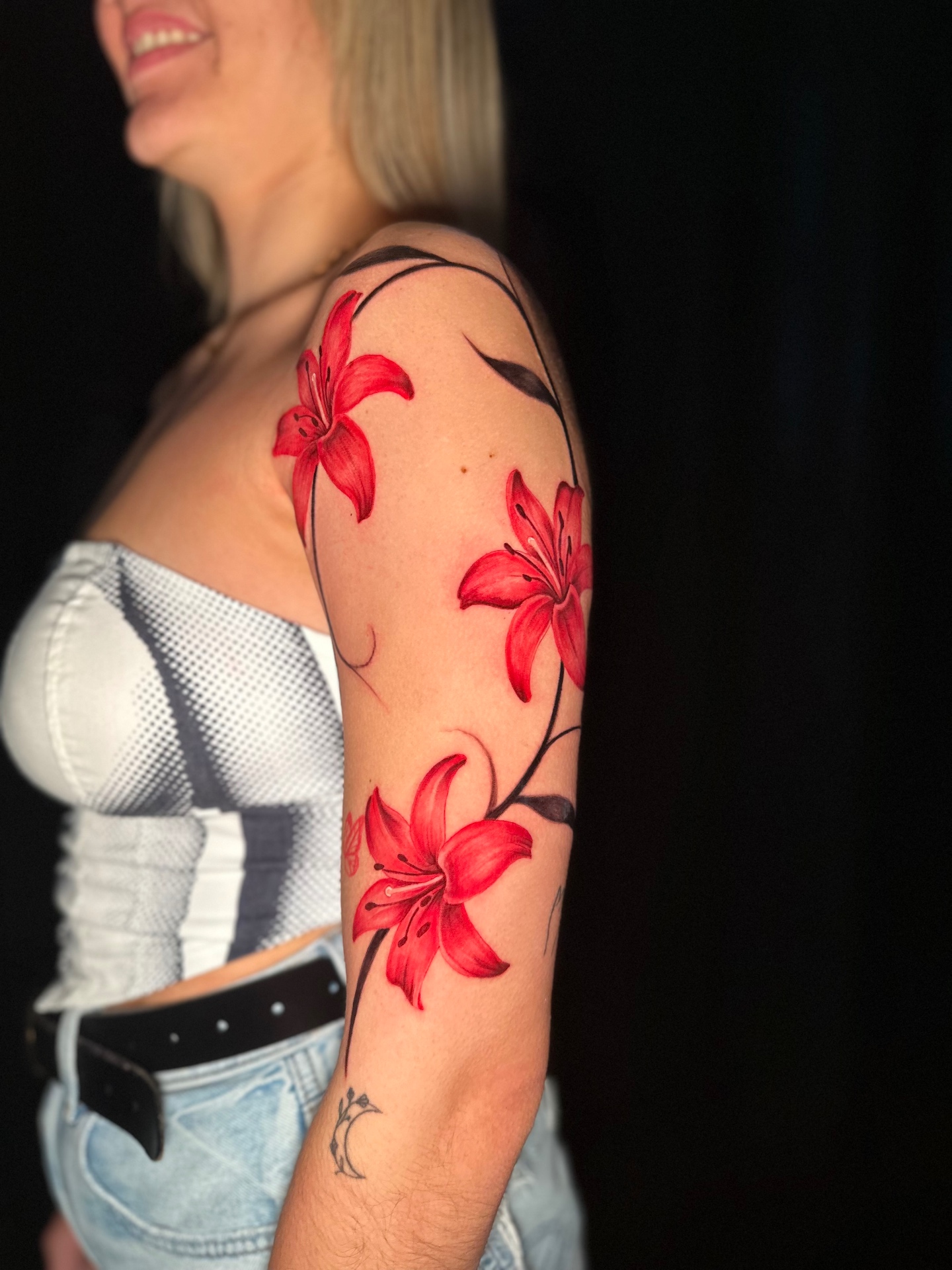 Vibrant red lily shoulder tattoo by Ramón Santiago at R INKS ARTS