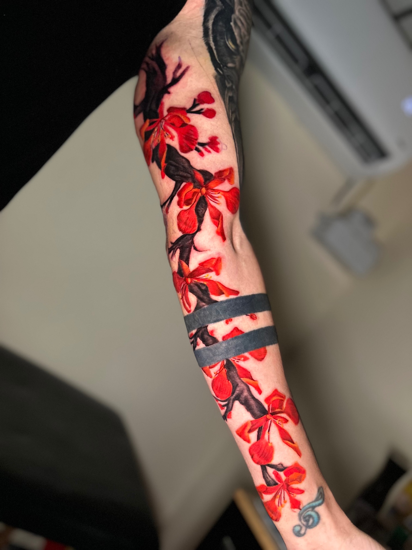 Vibrant red flower full-sleeve tattoo by Ramón Santiago at R INKS ARTS