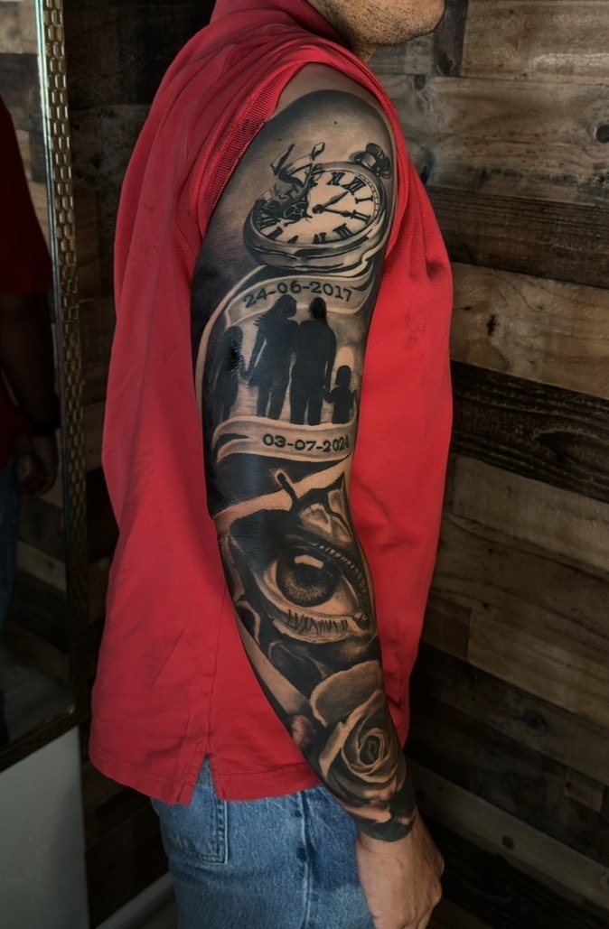 Black and grey memorial sleeve with pocket watch, family silhouettes, eye and rose by Ramón Santiago at R INKS ARTS