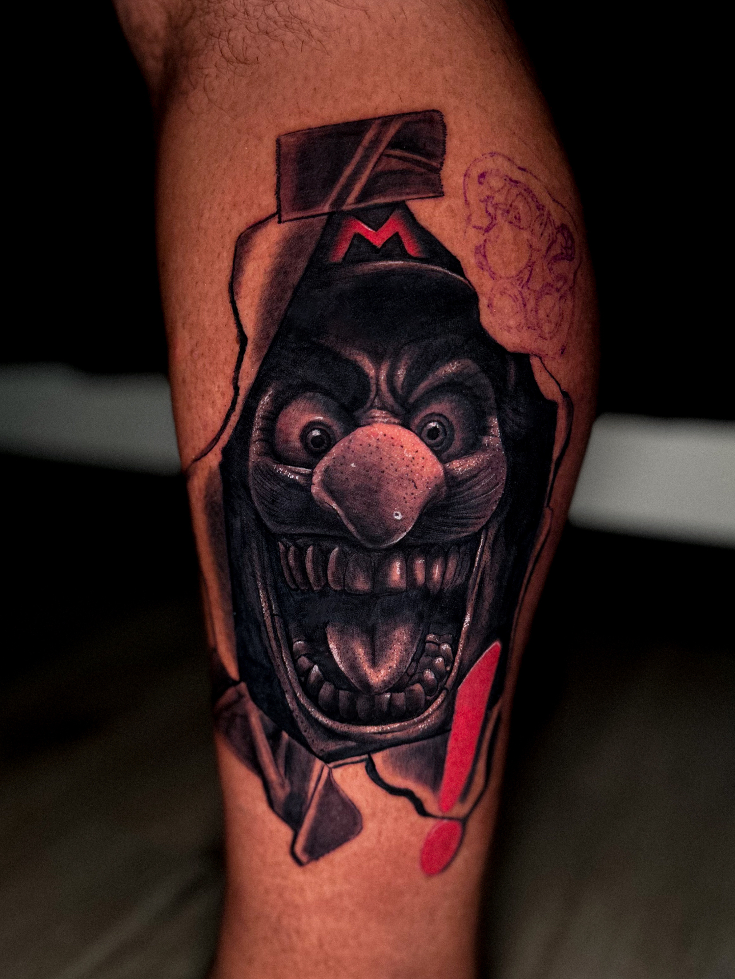 Black and grey grinning face tattoo with a cap by Ramón Santiago at R INKS ARTS