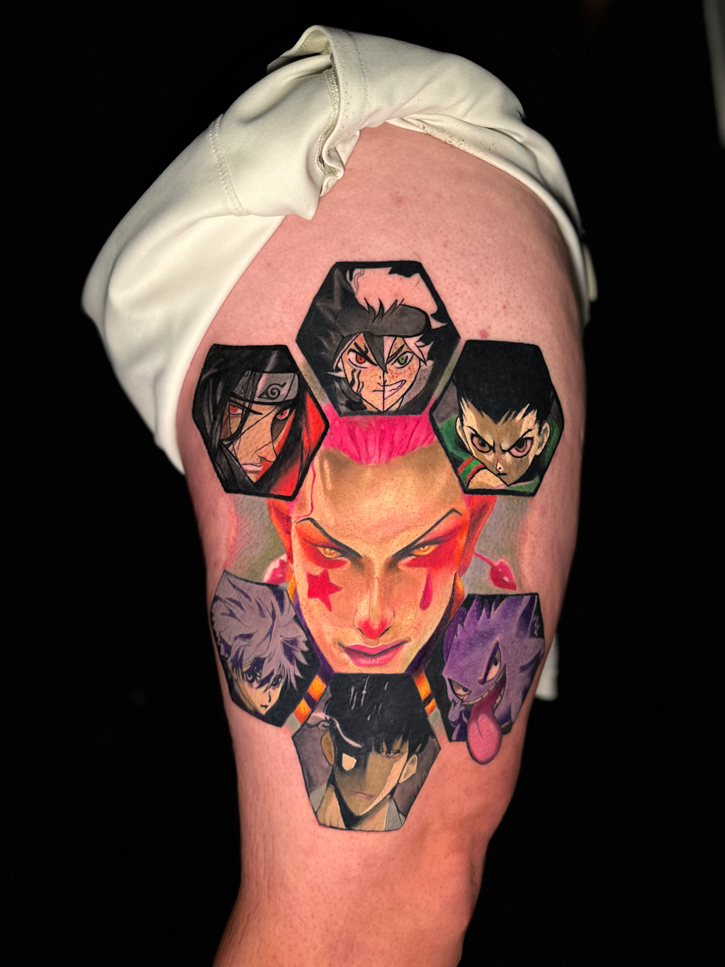 Colorful anime thigh piece with hexagonal frames and a clown face by Ramón Santiago at R INKS ARTS